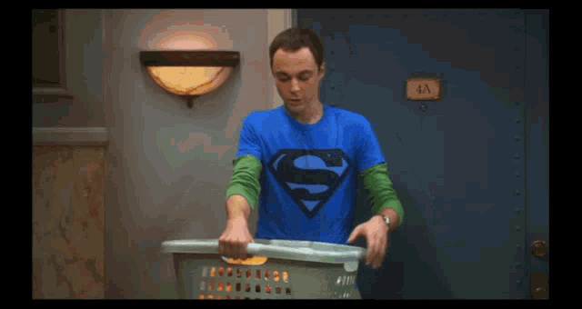 a man in a superman t-shirt is holding a laundry basket