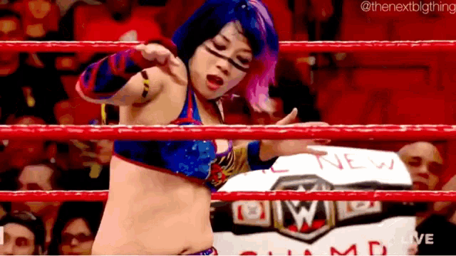 a woman is standing in a wrestling ring holding a sign that says new .