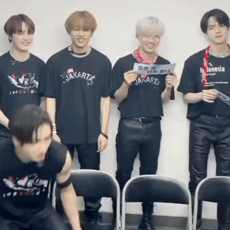 a group of young men are standing next to each other wearing black t-shirts .