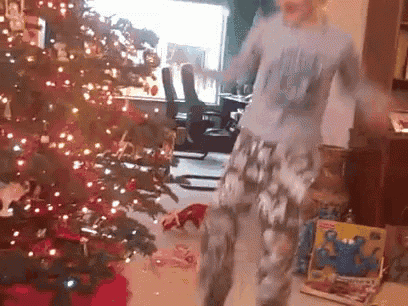 a woman is dancing in front of a christmas tree in a living room .