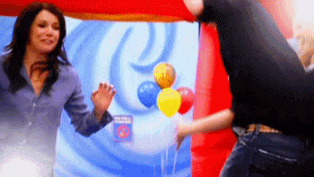 a man and a woman are dancing in front of balloons and a sign that says ' a ' on it