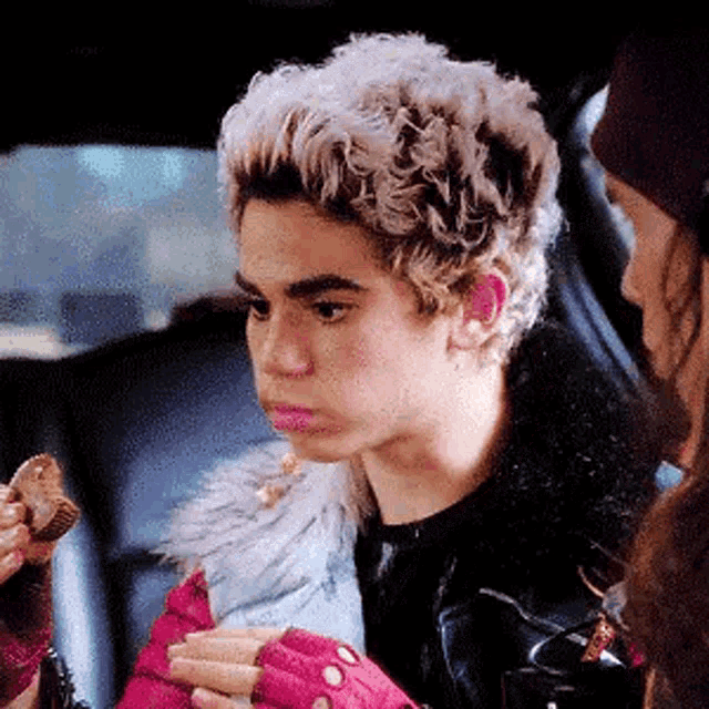 a young man is sitting in the back seat of a car eating a piece of food .
