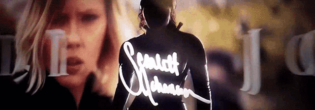 a woman is behind a man with the name scarlett johansson written on his back .