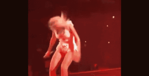 a woman is dancing on a stage in front of a crowd in a red dress .