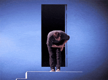 a man is bending over in front of a door that is open