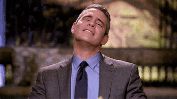 a man in a suit and tie is laughing with his mouth open