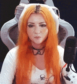 a woman with orange hair is sitting in a chair in front of a microphone