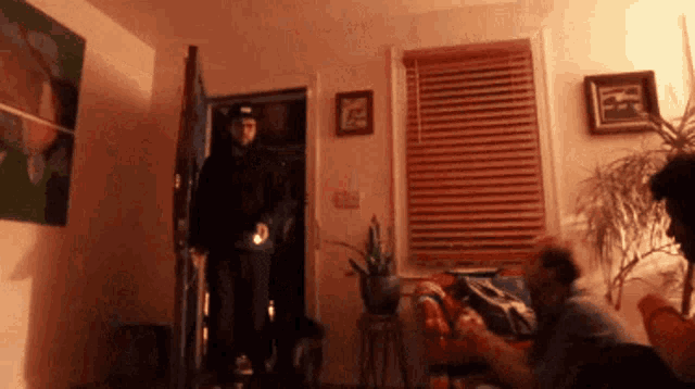 a man in a black hat is standing in a living room
