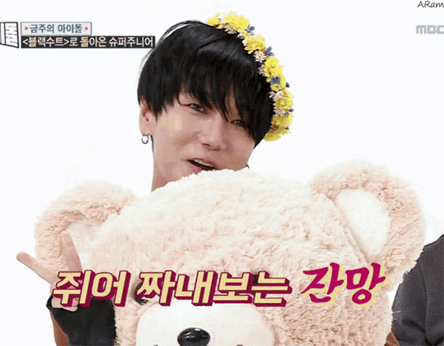 a man wearing a flower crown holds a teddy bear
