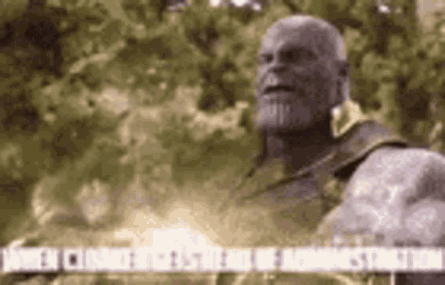 thanos from the movie avengers infinity war is standing in front of a forest .