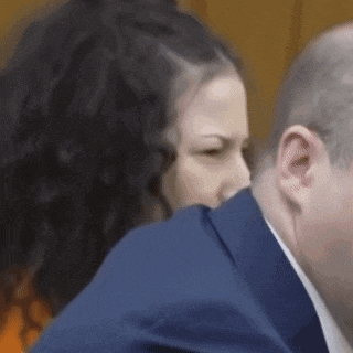 a woman in a blue suit is kissing a man on the cheek .