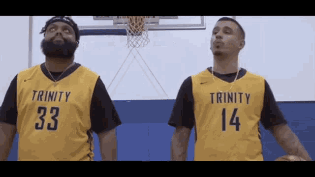 a man wearing a trinity jersey stands next to another man wearing a 14 jersey