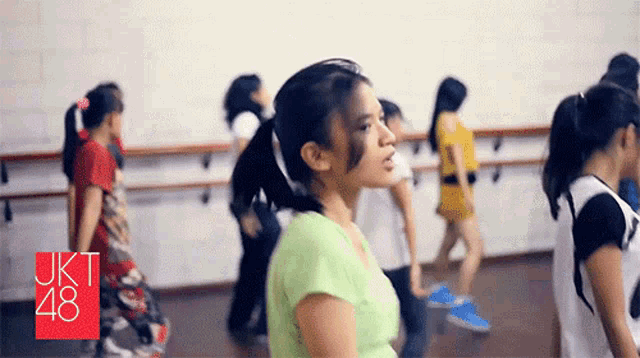 a girl in a green shirt stands in front of a sign that says jkt 48