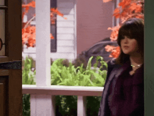 a woman in a purple jacket is standing in front of a green door