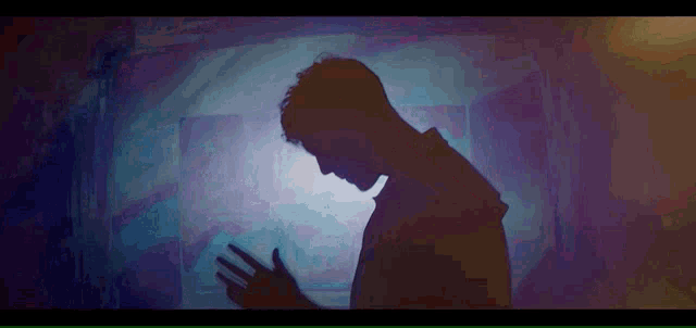 a silhouette of a man in a dark room with a blue light behind him
