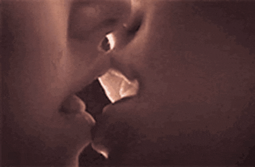 a close up of a woman 's lips kissing another woman 's .