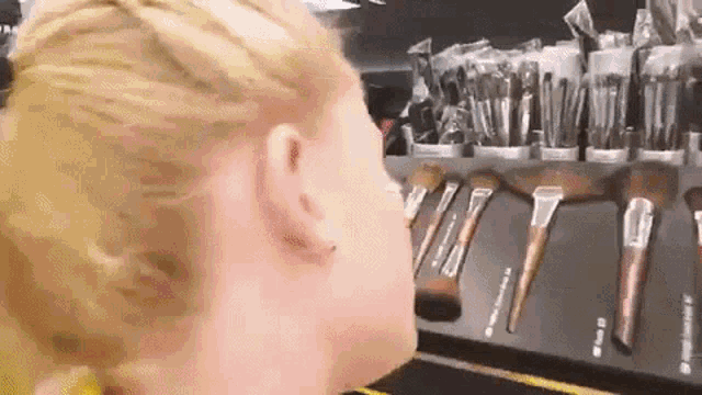 a woman is standing in front of a display of makeup brushes