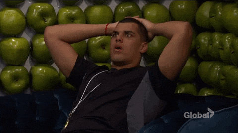 a man is sitting in front of a pile of green apples .