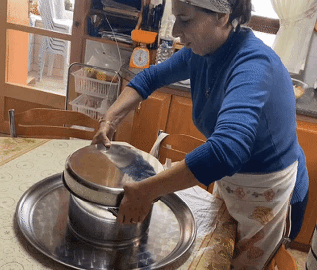 a woman in a blue sweater is holding a pot on top of a tray