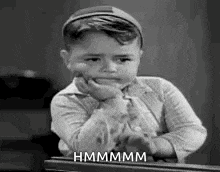 a little boy is sitting at a piano with his hand on his chin and making a funny face .