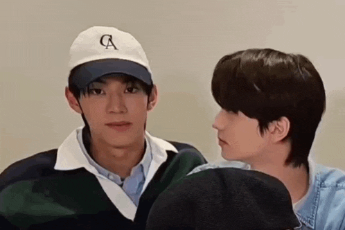 two young men are looking at each other while wearing hats and sweaters .