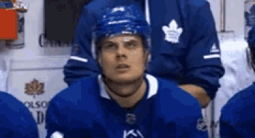 a hockey player wearing a helmet is sitting in the locker room .