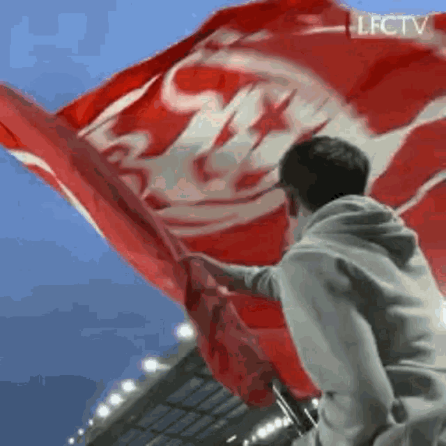 a man is holding a large red and white flag in his hands .