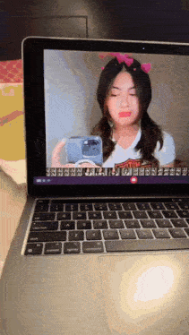 a woman is taking a picture of herself on a laptop screen