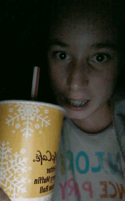 a young girl holding a cup that says mcdonald 's on it