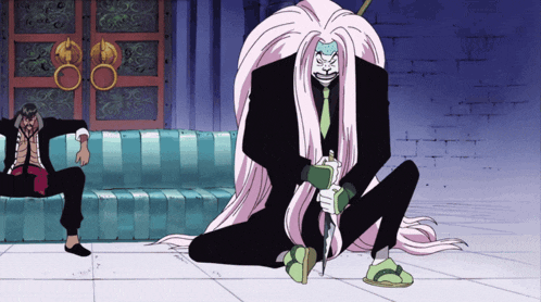 a man sits on a blue couch next to a man with long white hair