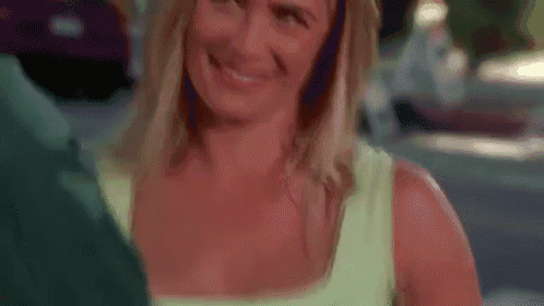 a woman in a green tank top is smiling and looking at a man in a green shirt .