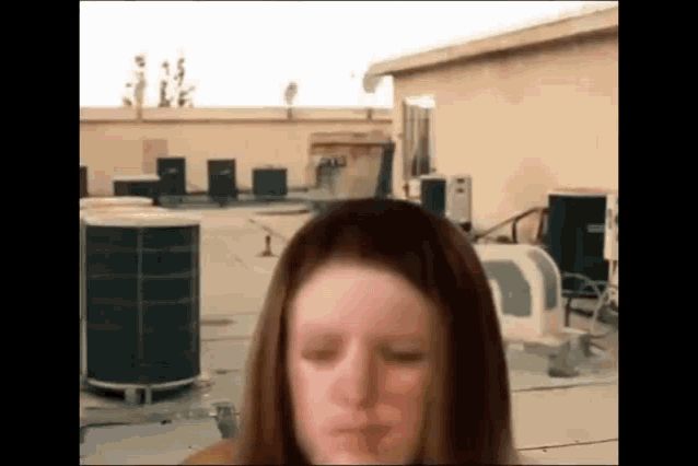 a woman is standing on a rooftop with her eyes closed