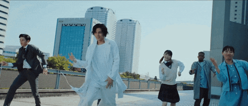 a group of people are dancing in front of a building that says aoi