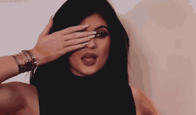 a close up of a woman covering her eyes with her hand with kyliefashionstyle written on the bottom