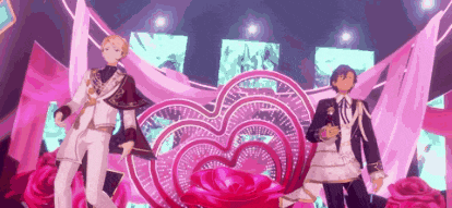two anime characters are standing next to each other on a stage in front of a heart shaped prop .