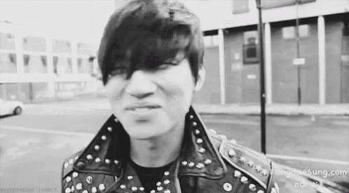 a black and white photo of a young man wearing a leather jacket .