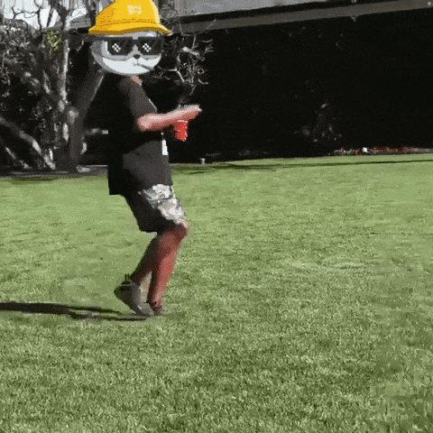 a person wearing sunglasses and a hard hat is standing in a grassy field .
