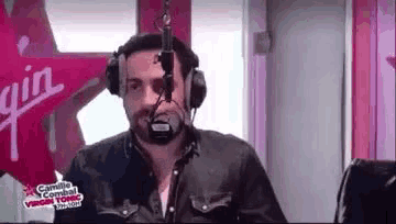 a man wearing headphones and a microphone is talking into a microphone in a radio studio .
