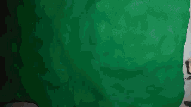 a stuffed gizmo with glasses is standing in front of a green wall