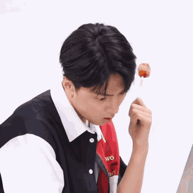 a young man is holding a lollipop with a surprised look on his face and the word wo on his shirt