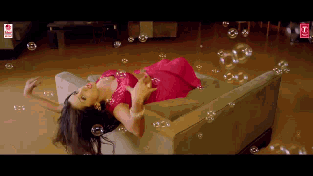 a woman in a red dress is laying on a couch with soap bubbles surrounding her