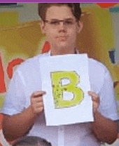 a man is holding a piece of paper with a letter b on it .
