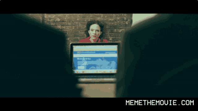 a woman sitting in front of a laptop with memethemovie.com on the bottom right