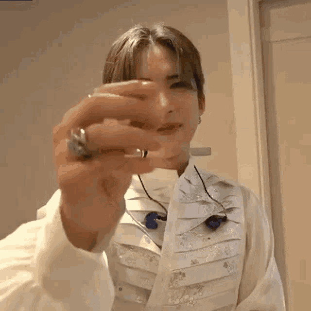 a man wearing a white shirt and a ring on his finger is holding a piece of paper in his hand .