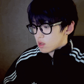 a man wearing glasses and a black adidas jacket