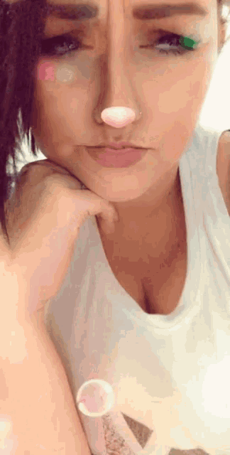 a woman wearing a white tank top has a pink nose and a green eye