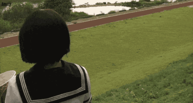 a girl in a sailor uniform looks out over a field