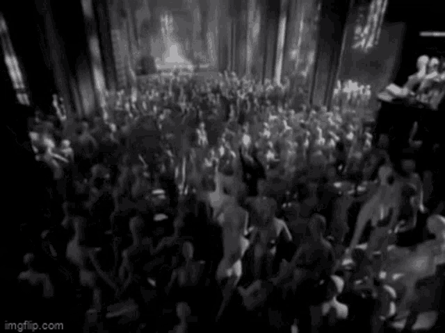 a black and white photo of a crowd of people dancing in a club .
