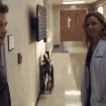 a man and a woman are standing in a hallway talking