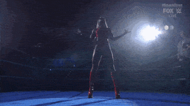 a woman in a red top is standing in a wrestling ring .